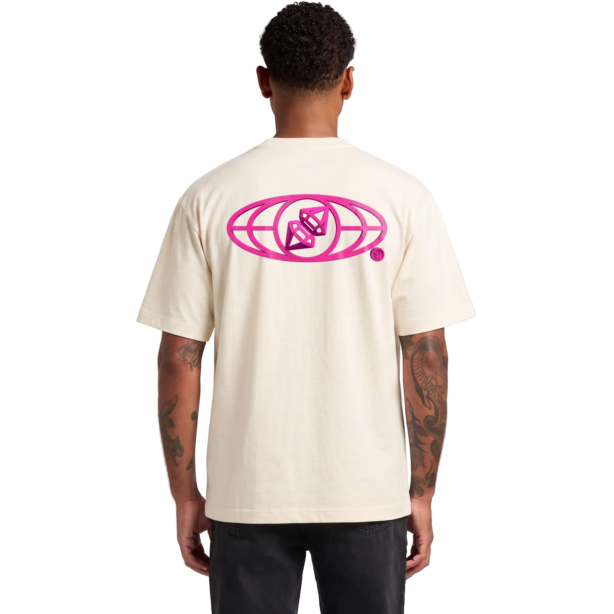 A man viewed from the back wearing a cream-colored t-shirt with a large hot pink graphic on the back, paired with black pants, against a light gray studio background.